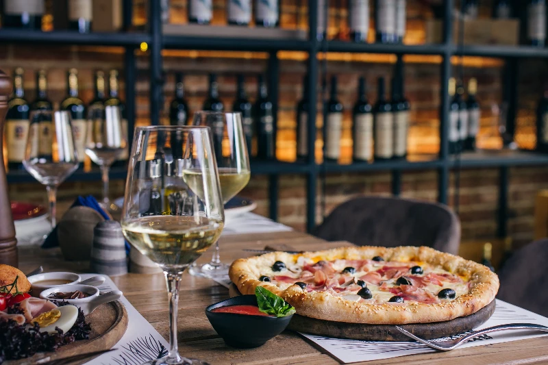 Blog 11 Pizza with prosciutto and olives with wine in restaurant